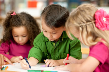 Young children coloring or writing in school classroom