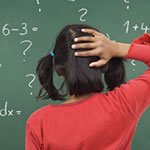 Young femaile student having difficulty with math problem on chalkboard displaying symptoms of Dyscalculia.