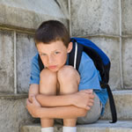 Young boy sitting alone holding his knees
