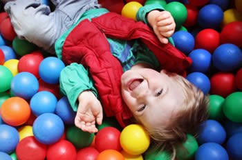 Young child playing in children's ball pit.